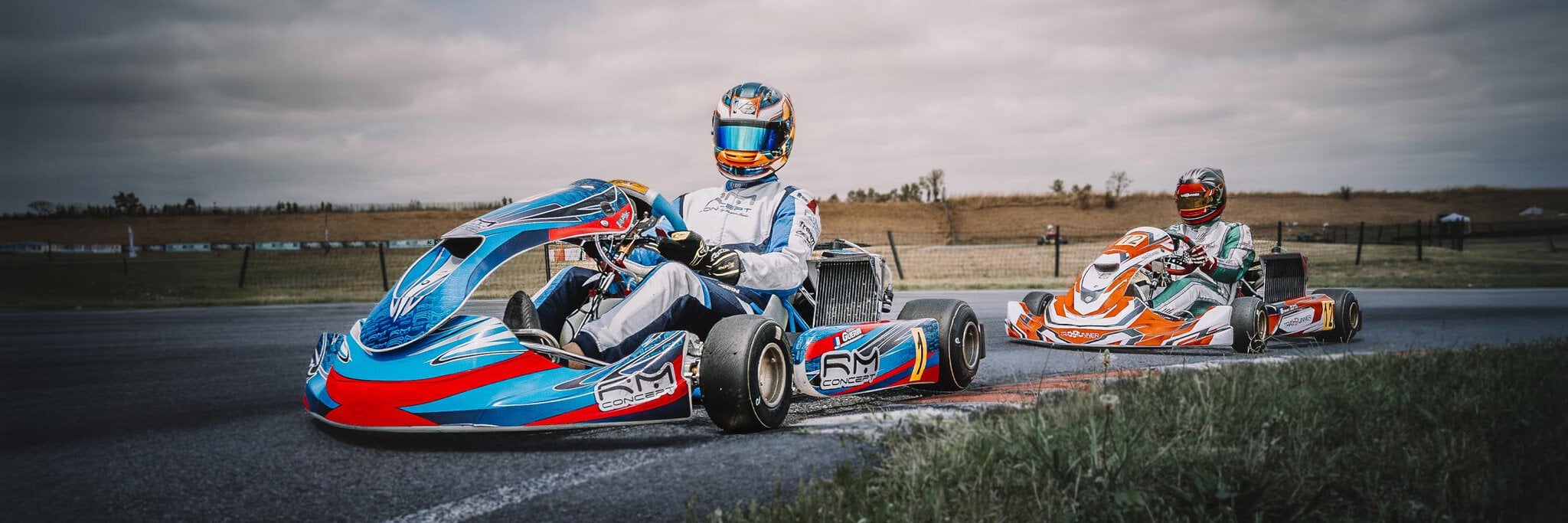 Deux karts RM Concept en duel en sortie de virage sous un ciel dramatique, reportage karting artistique Kart'Inside par Frantz Meyers photographe sportif à Castres.